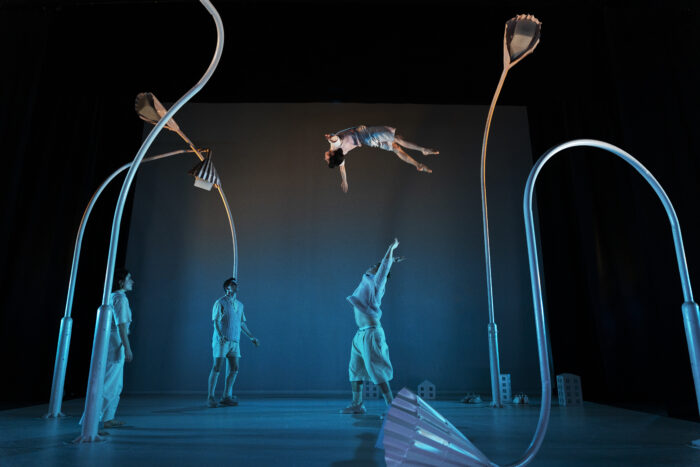 Fyra cirkusartister står på scen och en kastas i luften.