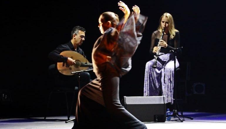 En flamencodansare och två musiker på scen spelar och dansar.